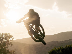 mountain biker jumping with sunset and mountains